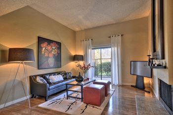 Living Room with Wood Inspired Floors, Black Sofa, Lamps, Painting and Window at Fountains of Fair Oaks, Fair Oaks California